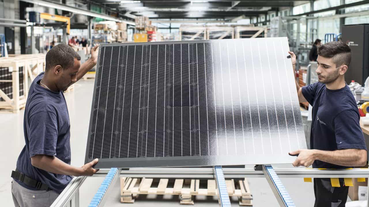 Des employés transportent un panneau solaire